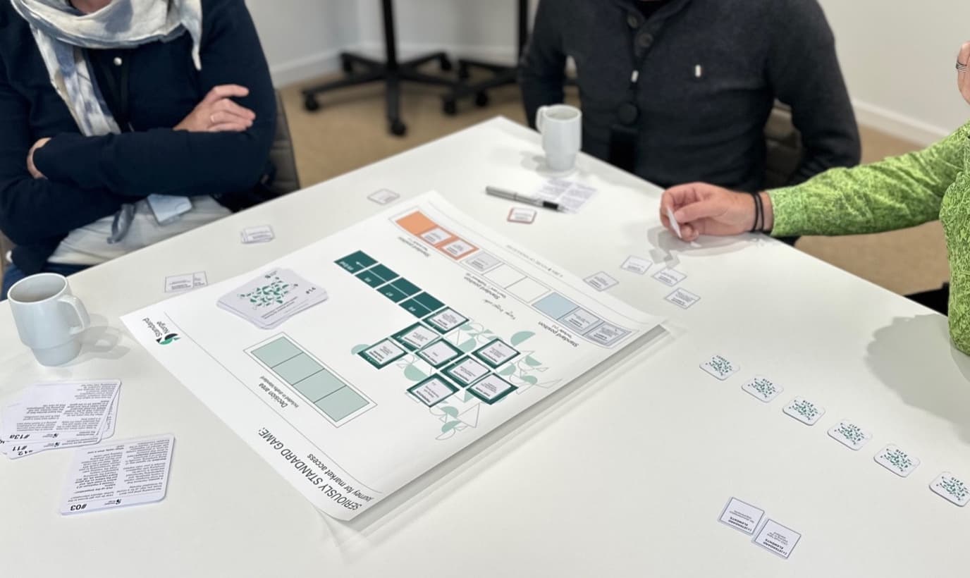 Participants discussing the Seriously Standard Game around the game board