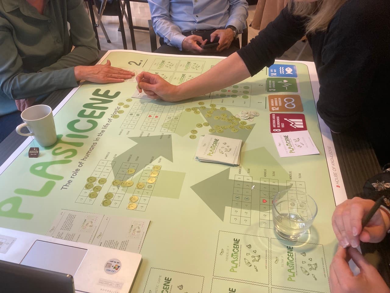 Participants playing the Plasticene Serious Game around the game board